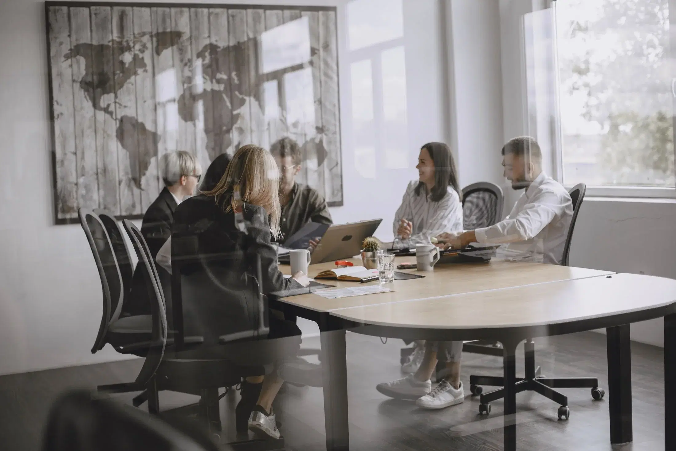 Professionals collaborating around a conference table in a bright, glass-walled office